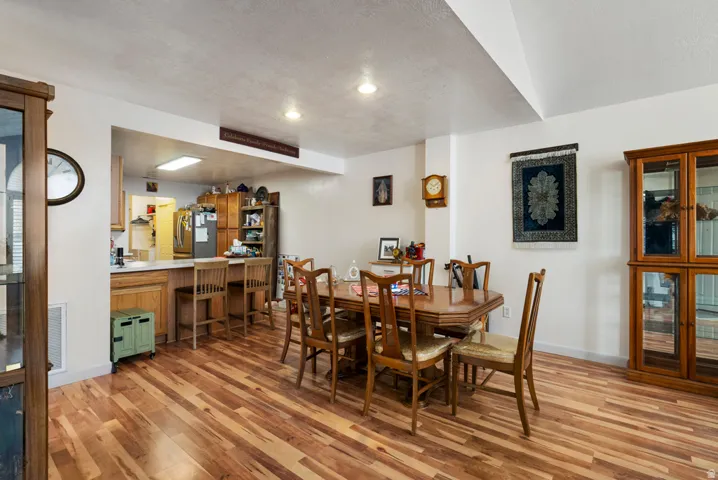 Spacious dining area featuring wood-finish flooring, recessed lighting, and a kitchen pass-through with a breakfast bar
