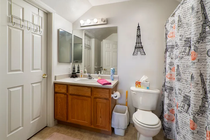 Bathroom featuring a wood-finish vanity with a single basin sink and laminate countertop