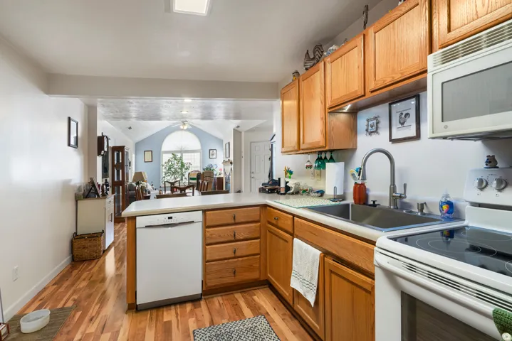 Kitchen featuring wood-finish flooring, light-toned cabinetry, light countertops, and a stainless steel sink with a modern faucet