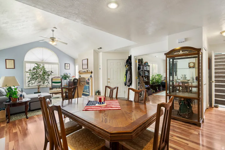 Interior space featuring wood-finish flooring, vaulted ceilings, and a large arched window with horizontal blinds