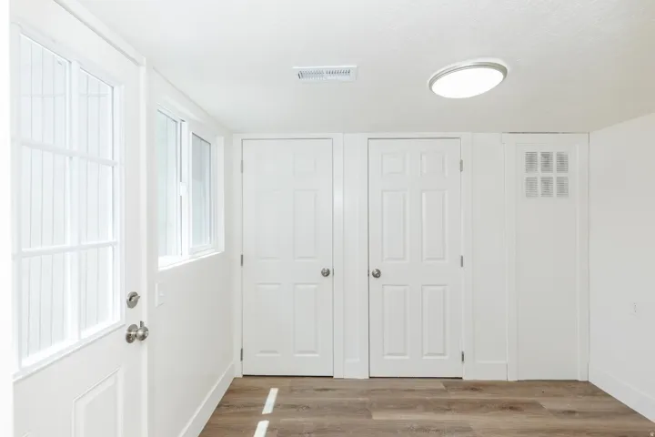 Entryway featuring wood-finish flooring, white paneled doors, and a window with a multi-pane design