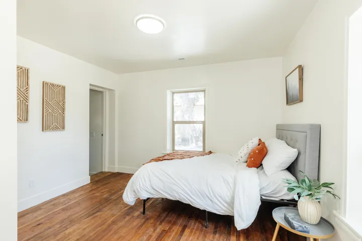 Bright interior space featuring a window, wood-finish flooring, white walls, a flush-mount ceiling light, and a doorway