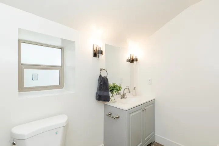 Bathroom vanity with a white countertop, brushed nickel faucet, and a light gray base cabinet