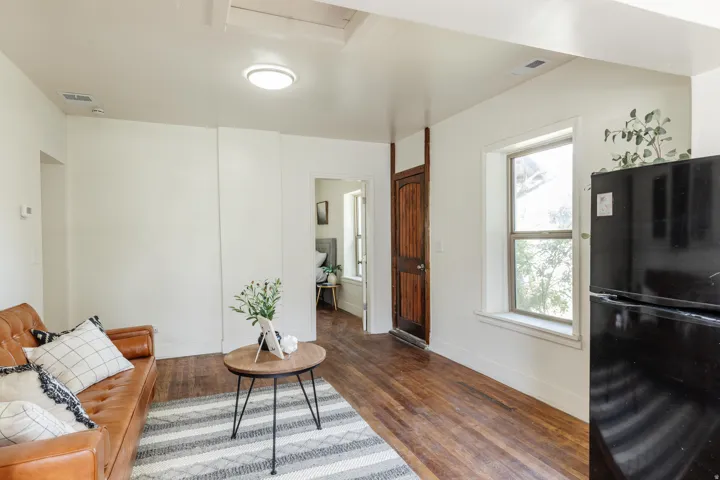 Open-concept living area with wood-finish flooring, bright white walls, a recessed ceiling light, and a double-hung window