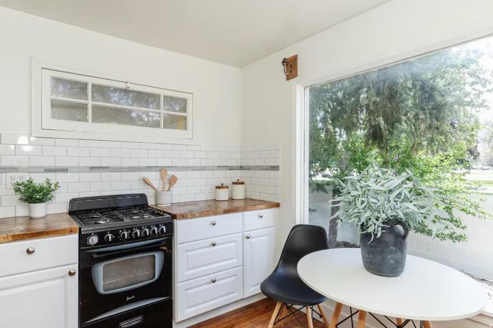 Kitchen featuring a black gas range, white cabinetry with silver hardware, and wood-finish countertops