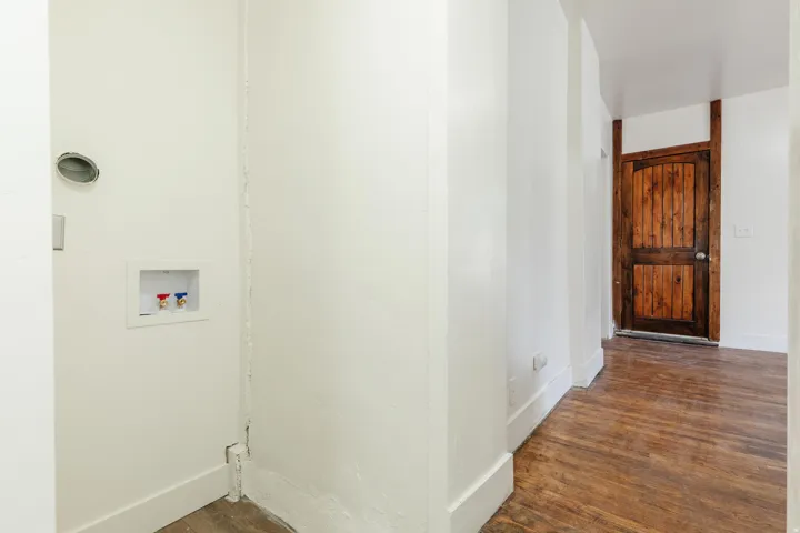 Dedicated laundry area with hookups, white walls, and wood-finish flooring