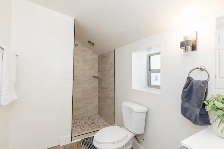 Shower enclosure featuring natural stone-look wall tiles and a pebble floor