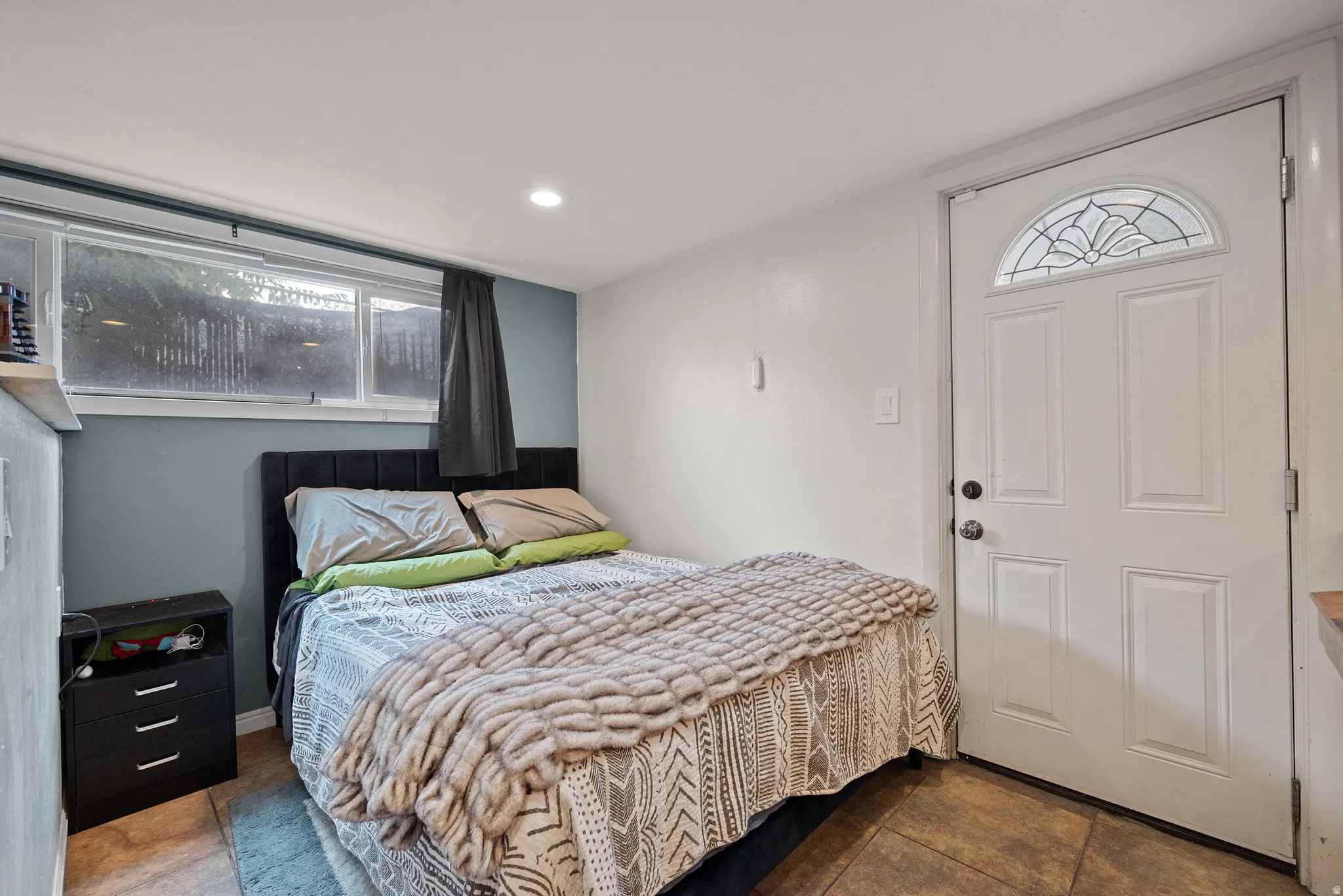 Room featuring tile flooring and a white paneled entry door with an arched decorative glass insert