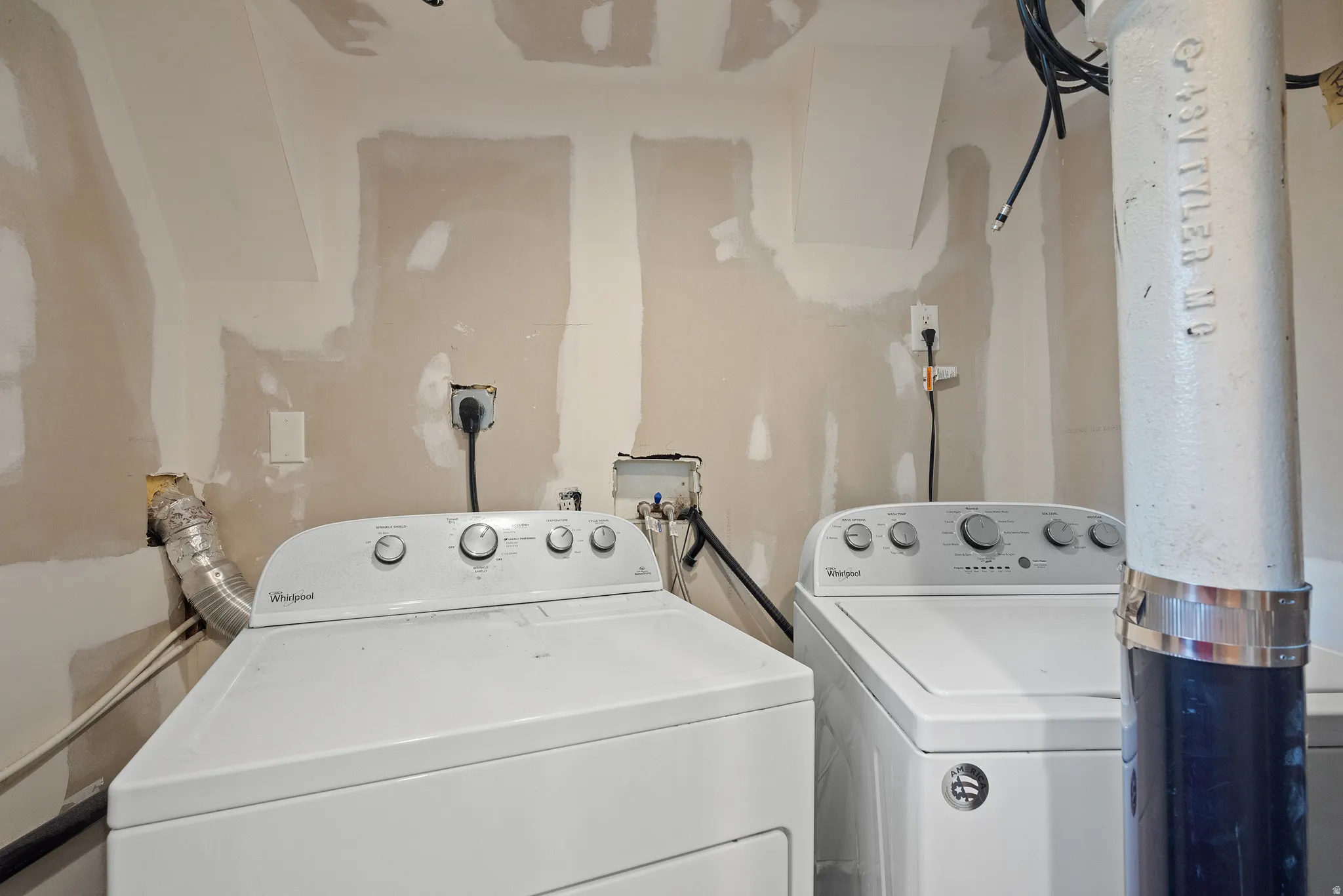 Dedicated laundry area featuring a white top-loading washing machine and a white front-loading dryer, with visible electrical outlets and plumbing connections