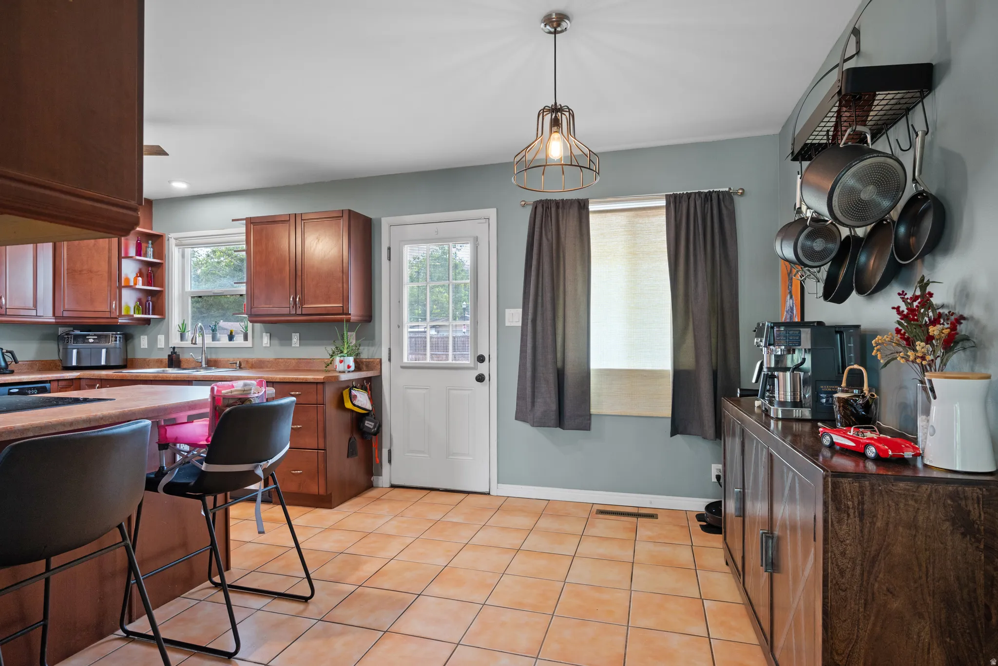 Kitchen featuring wood cabinetry, warm-toned tile flooring, and a peninsula with countertop seating