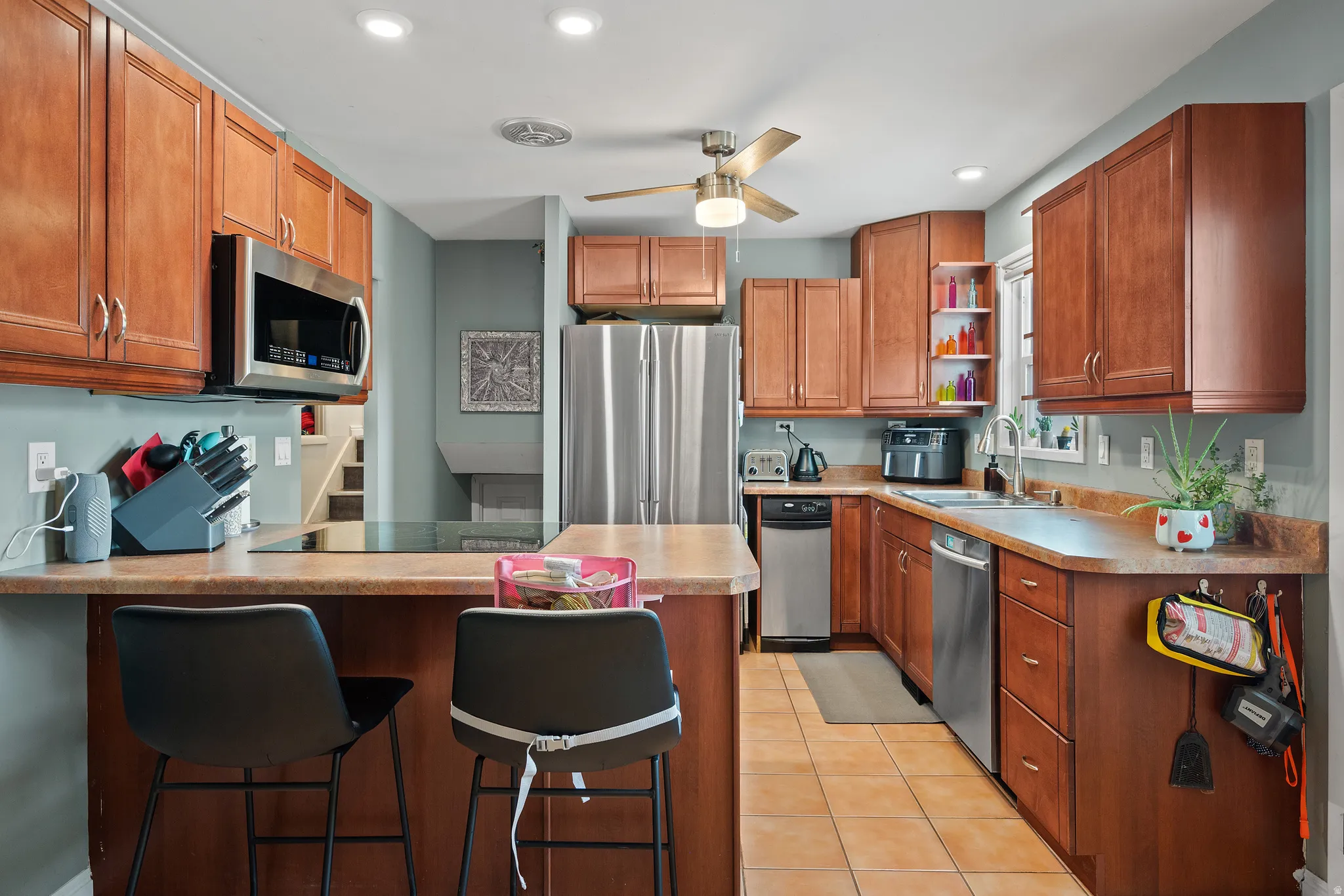 Modern kitchen featuring wood-finish cabinetry, stainless steel appliances, and a built-in cooktop with an overhead microwave