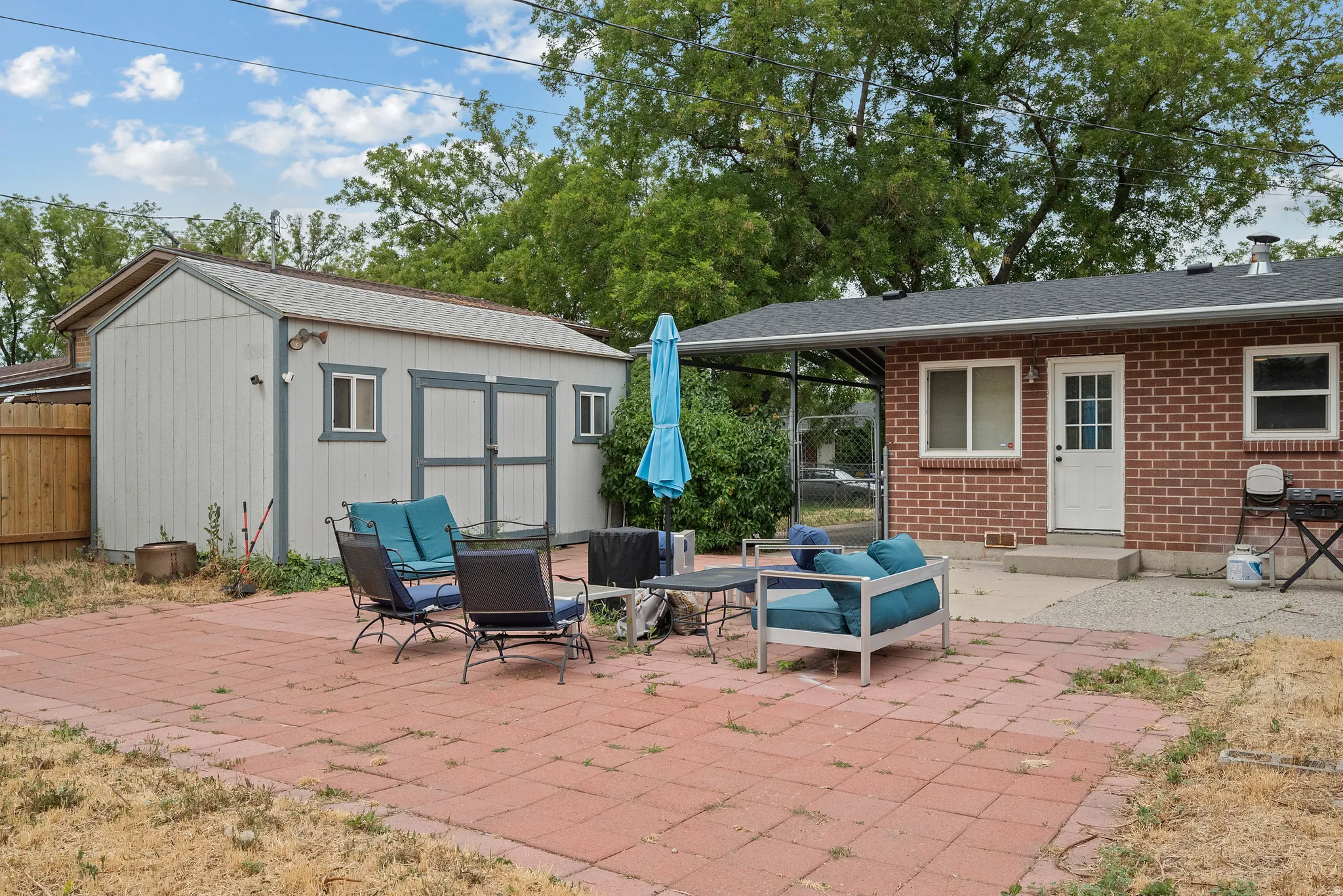 Expansive paver patio with a detached storage shed featuring double doors and side windows