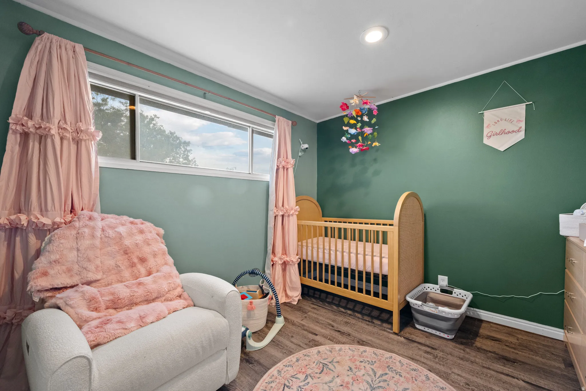 Room featuring wood-finish flooring, a bright window, and an accent wall