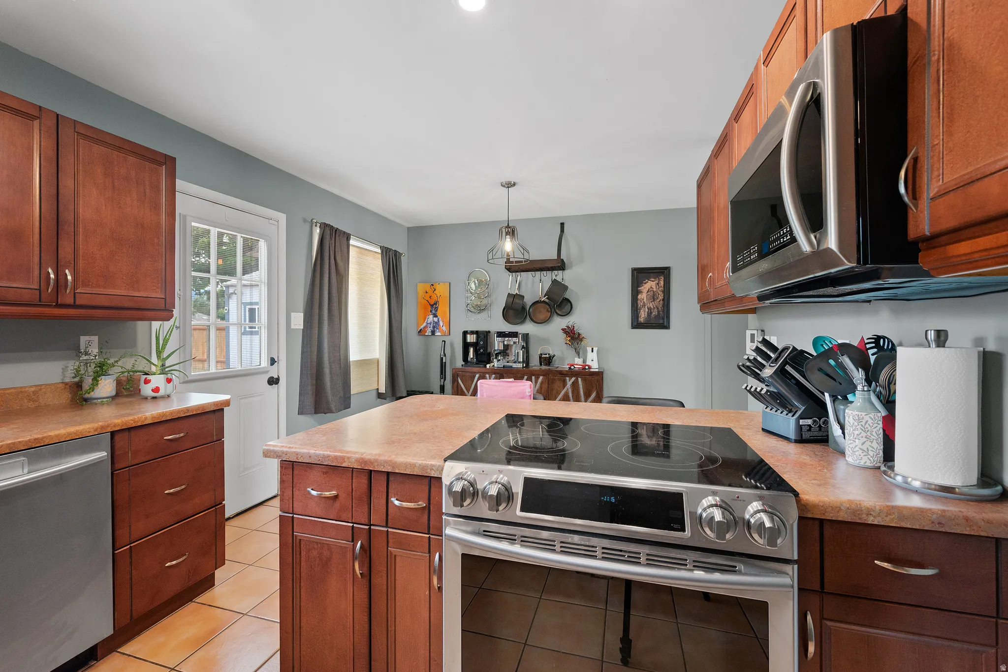 Contemporary kitchen featuring a stainless steel range with a flat cooktop, matching built-in microwave, and warm-toned cabinetry