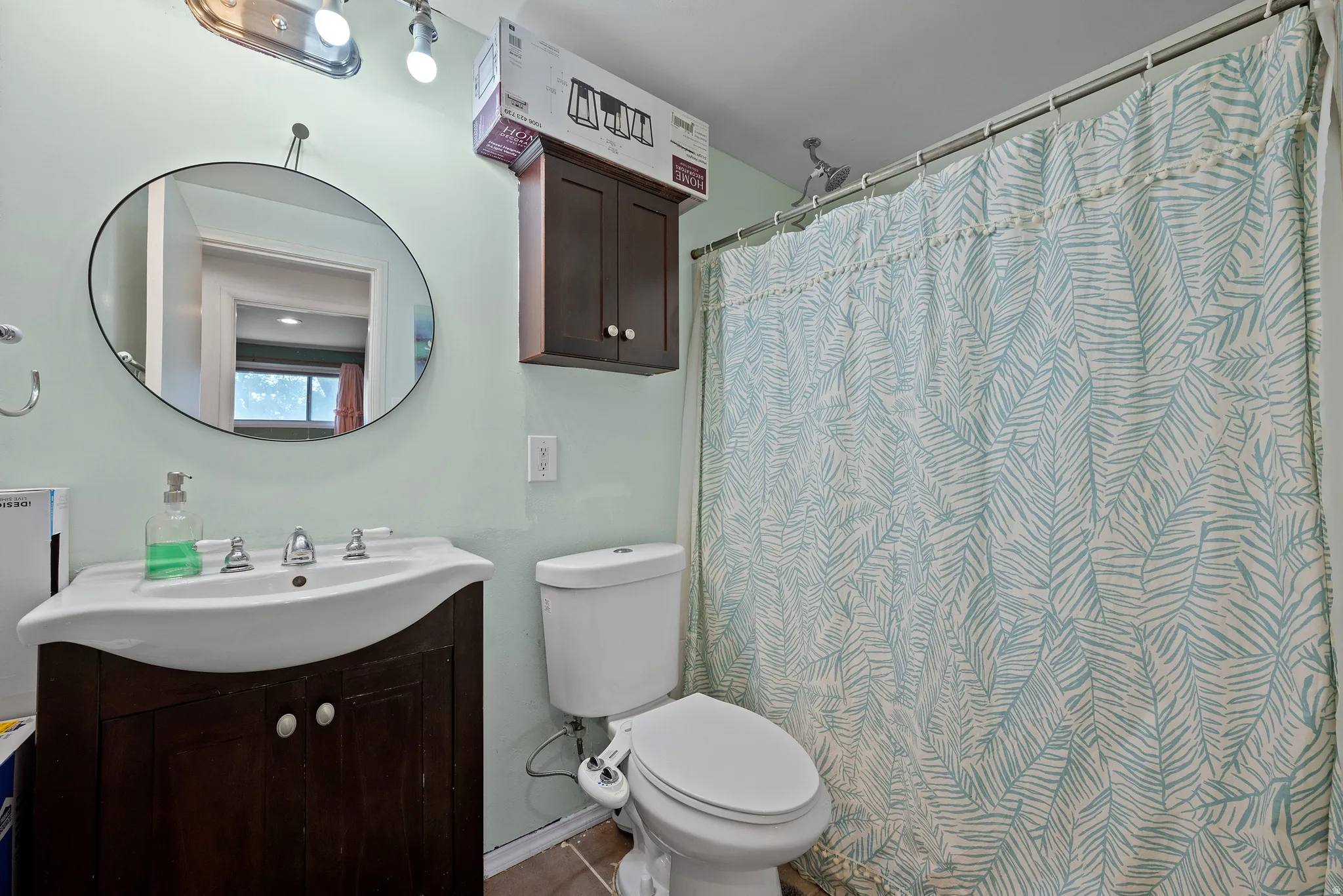 Bathroom featuring a dark wood-finish vanity with an integrated sink, polished chrome faucet, and an oval mirror