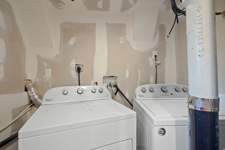 Dedicated laundry area featuring a white top-loading washing machine and a white front-loading dryer, with visible electrical outlets and plumbing connections