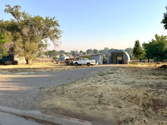 Expansive gravel lot featuring a large Quonset hut structure and an additional storage shed