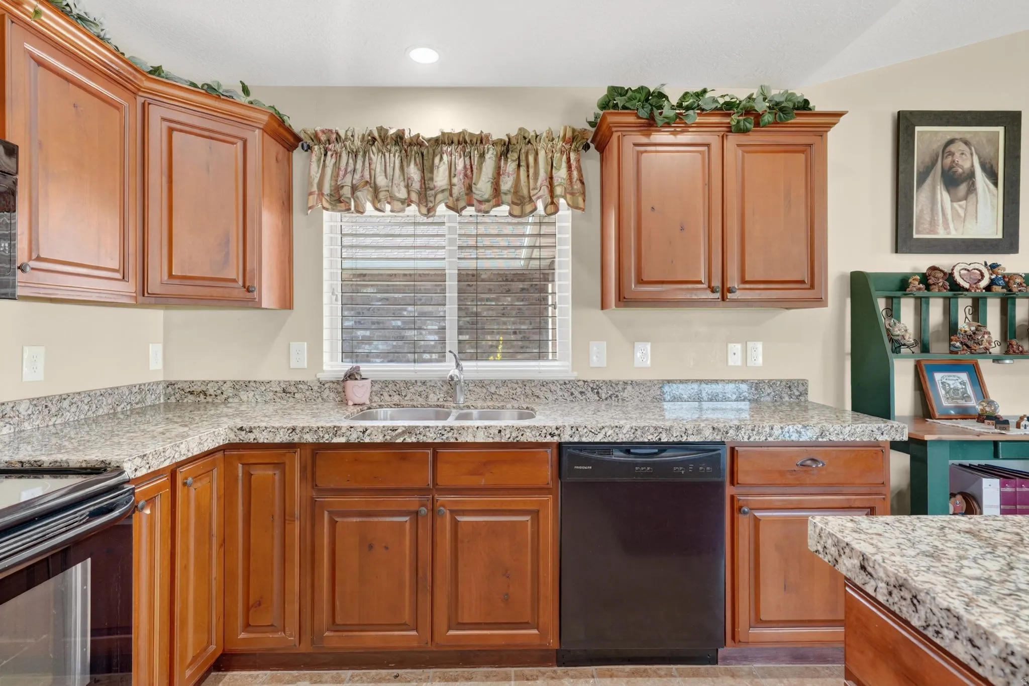 Kitchen featuring wood cabinetry, light-colored countertops, a double basin sink, and a black dishwasher
