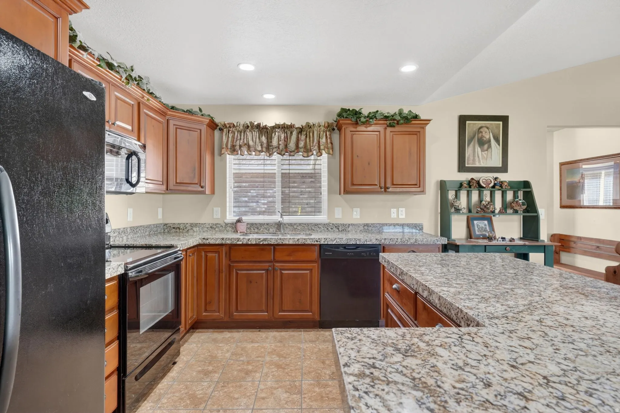 Spacious kitchen featuring extensive cabinetry, ample counter space with stone-finish surfaces, and recessed lighting