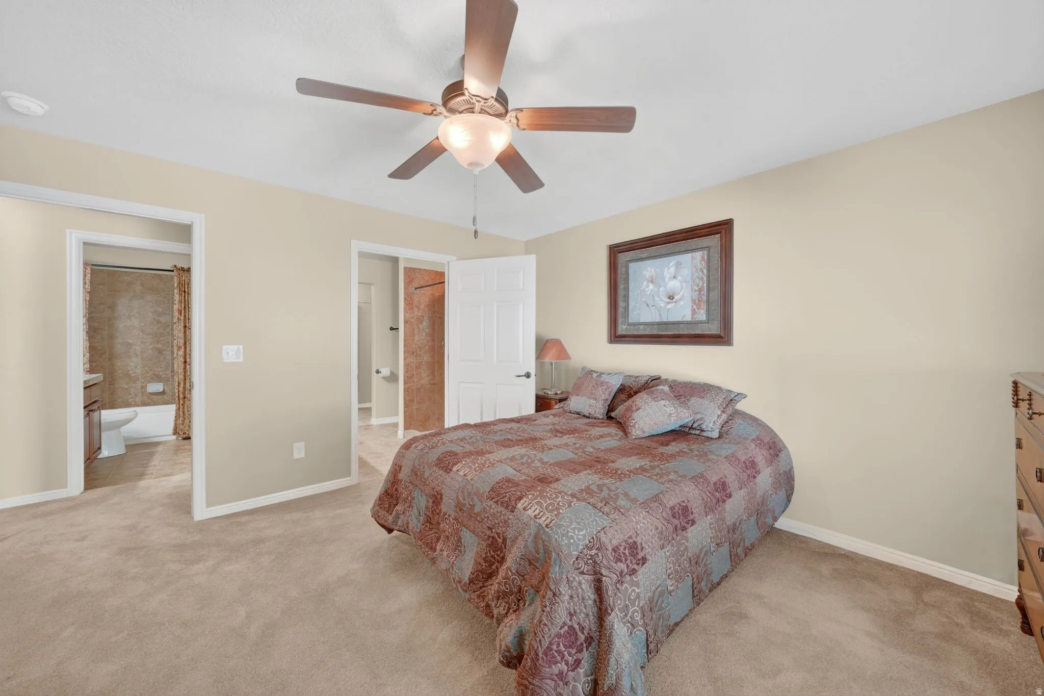 Carpeted bedroom featuring a ceiling fan with light fixture, neutral wall color, and white trim