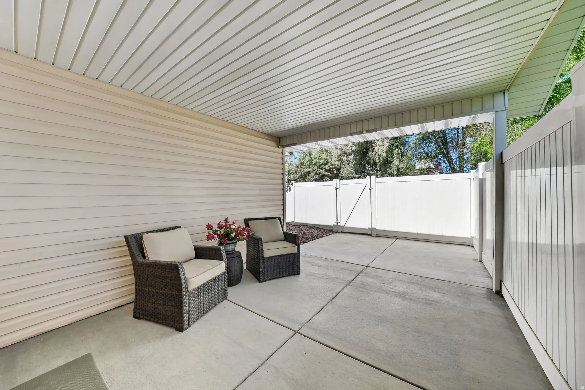 Covered patio area featuring a concrete slab, a slatted ceiling, and an exterior wall with horizontal siding