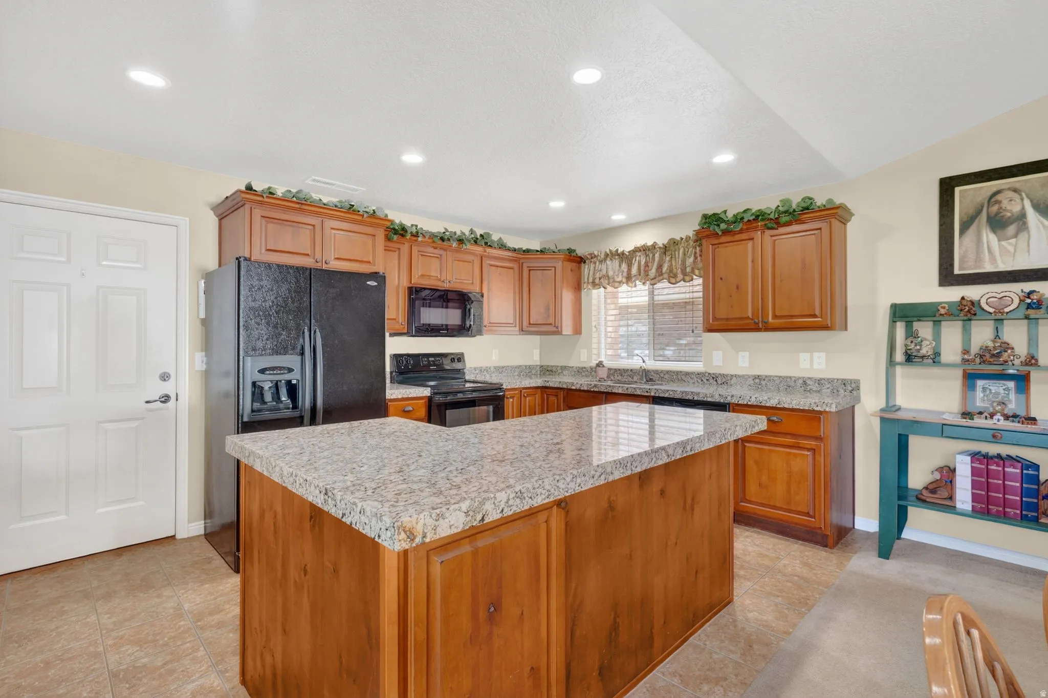 Kitchen featuring a central island with a light-toned countertop, wood-finish cabinetry, recessed lighting, tile flooring, and a window with blinds