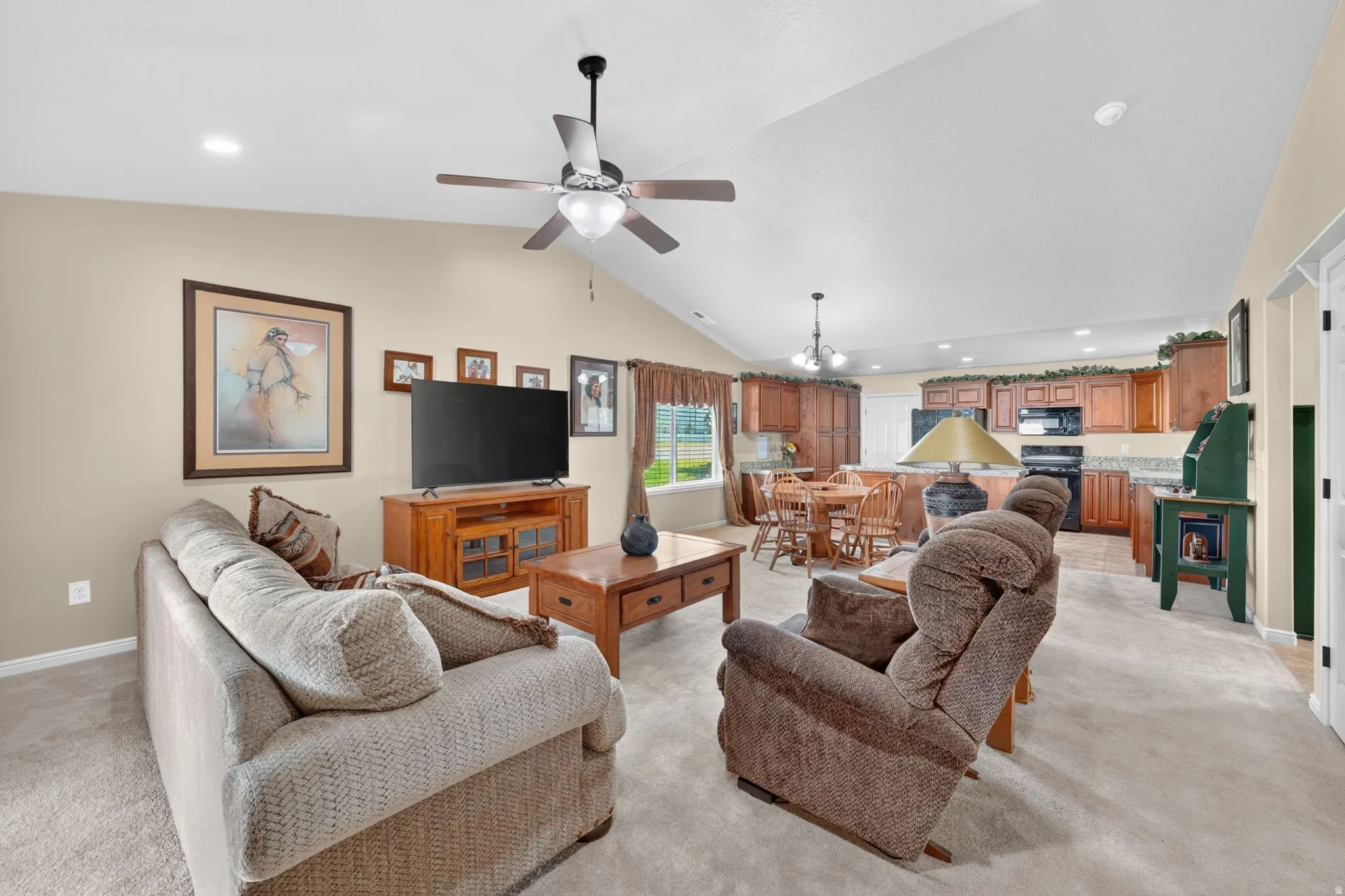 Spacious open-concept living area featuring a vaulted ceiling with a ceiling fan