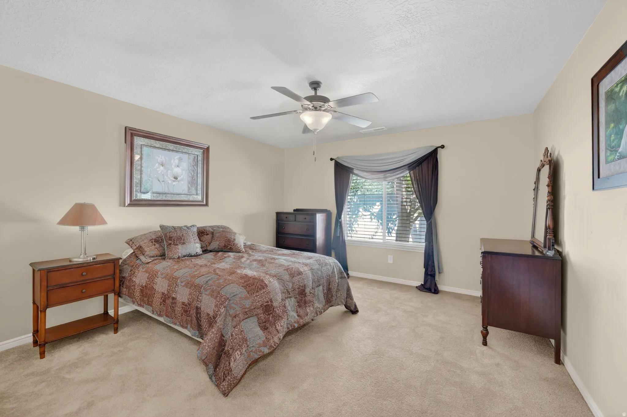 Carpeted bedroom featuring neutral wall tones, a ceiling fan with integrated lighting, and window blinds