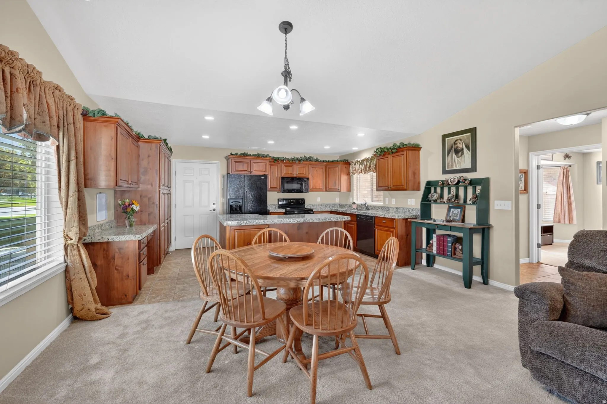 Open-concept dining and kitchen area with recessed lighting and a central chandelier