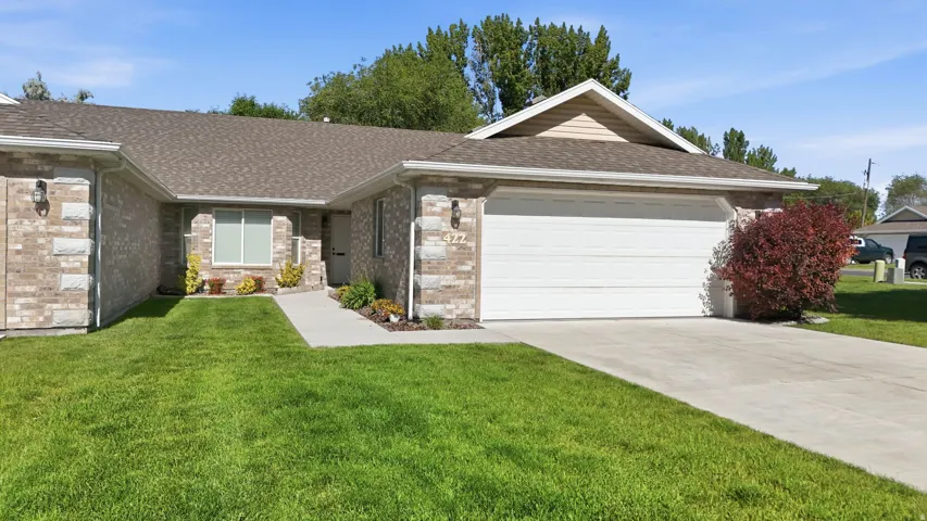 Brick and stone facade residence featuring an attached two-car garage, concrete driveway, and a front walkway