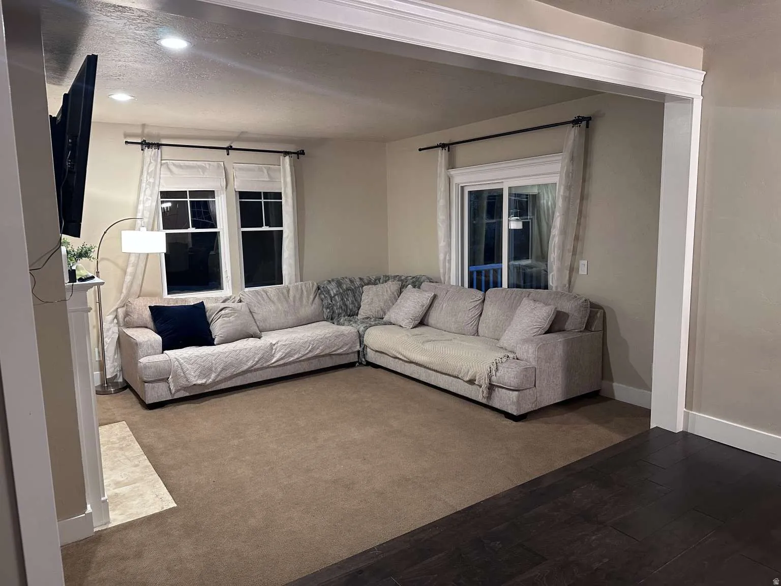 Open concept living space featuring recessed lighting, a fireplace with a light-toned tile hearth, and dark wood-finish flooring transitioning to carpet