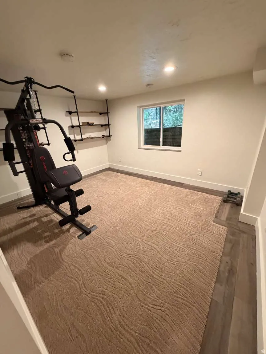 Versatile room featuring a window, recessed lighting, and a combination of patterned carpet and wood-finish flooring