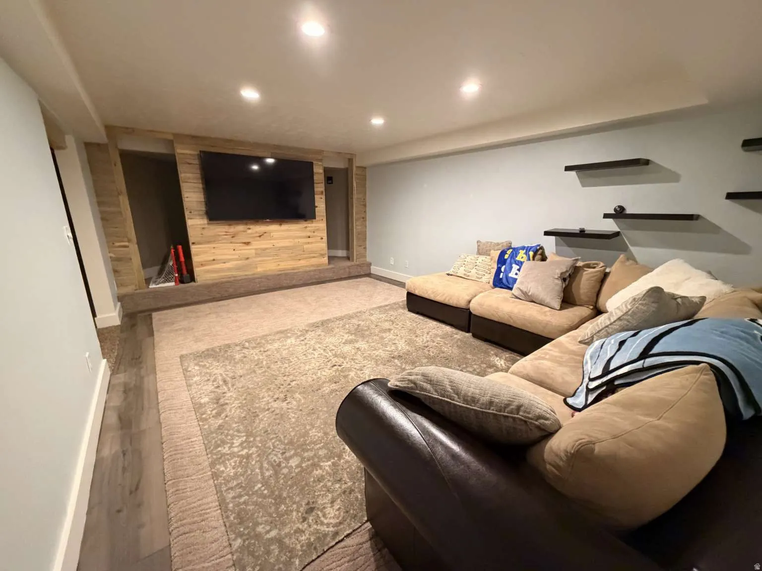 Entertainment room featuring a wood-panel accent wall with built-in media display