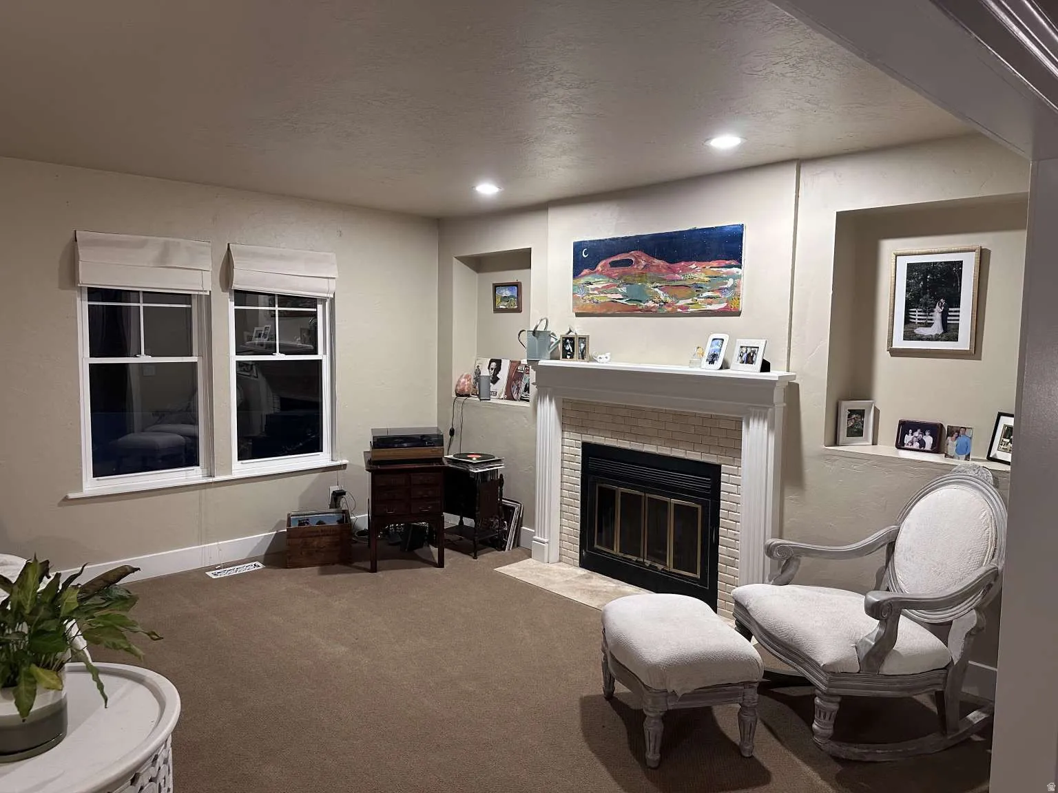 Living area featuring a fireplace with a white mantel and tile surround, two windows with white trim, built-in shelving, and recessed lighting