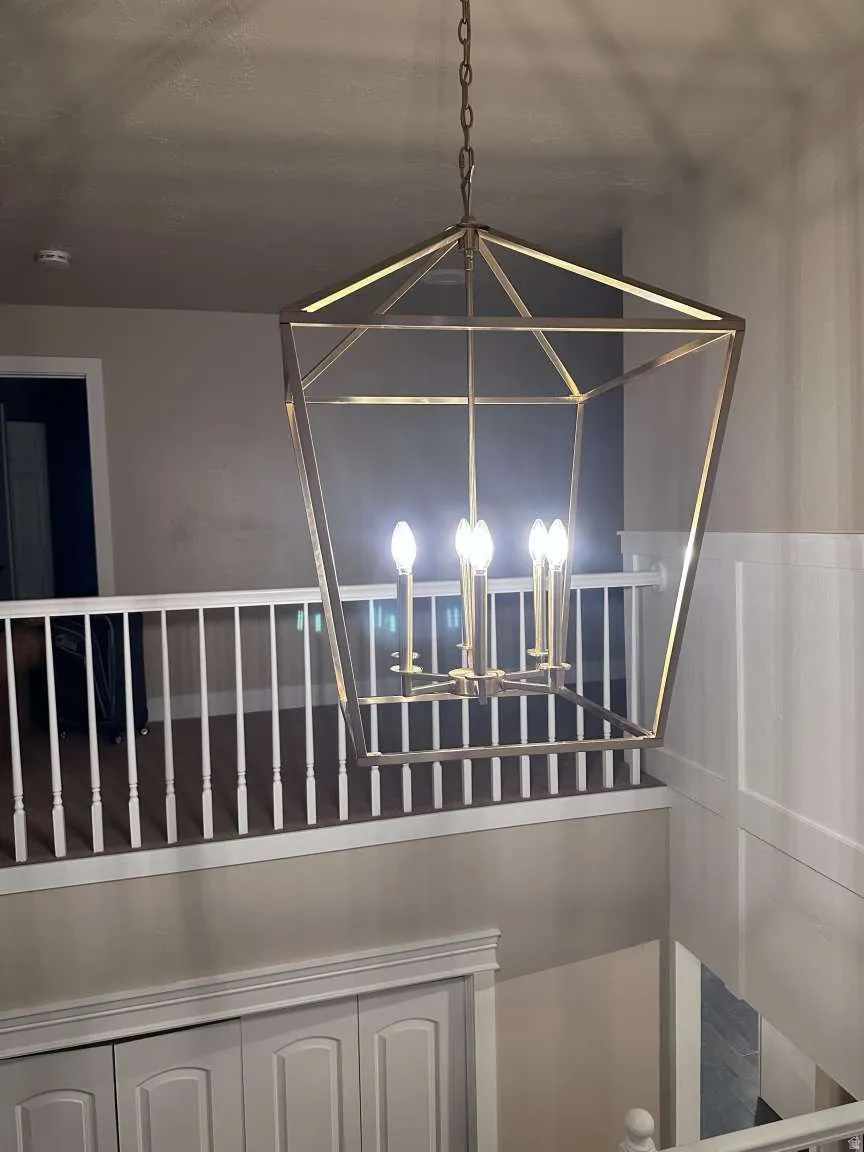 Geometric chandelier with a metallic finish, illuminating the two-story entry