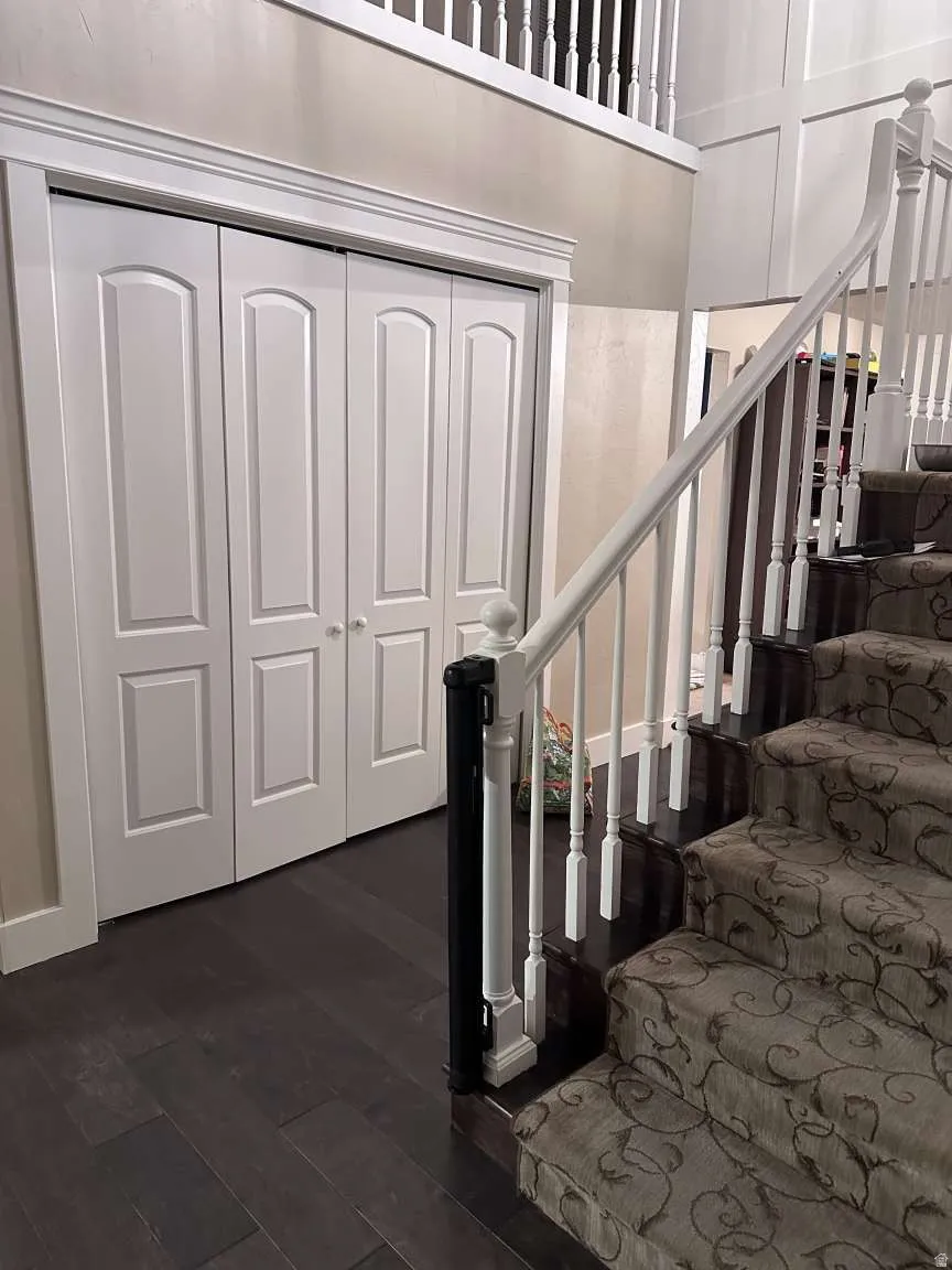 Dark wood-finish flooring complements the detailed carpeted staircase with white balusters