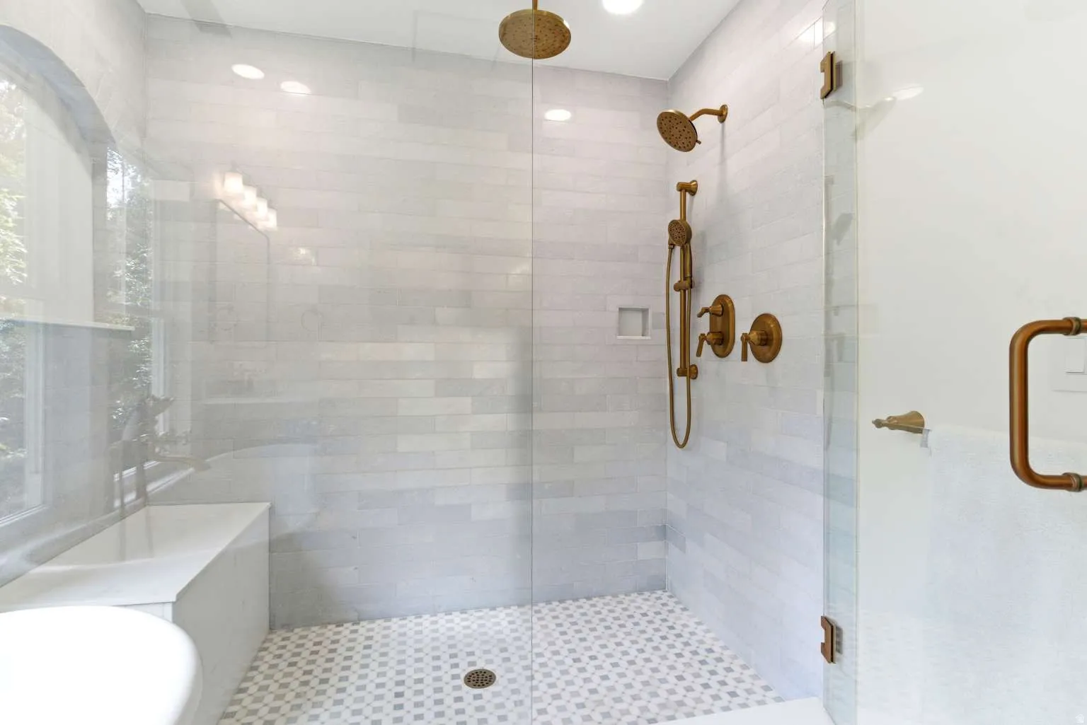 Glass-enclosed shower featuring dual shower heads, integrated bench seating, and brass fixtures