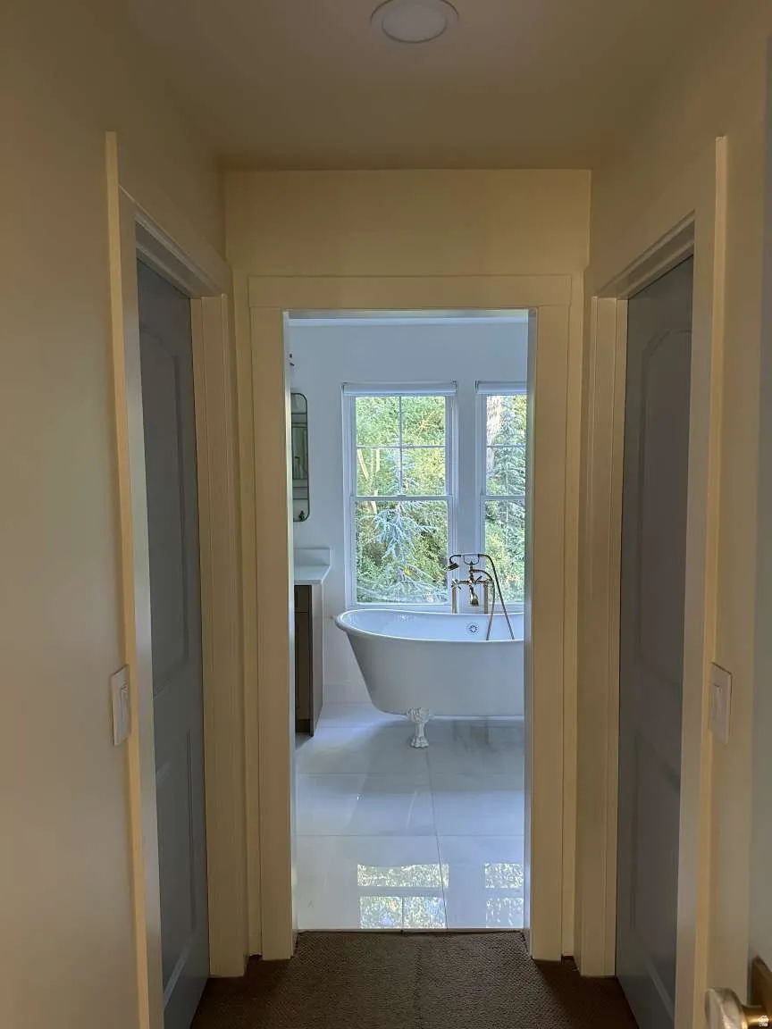 Light-filled bathroom featuring a freestanding clawfoot tub with a floor-mounted fixture, large-format tile flooring, and a three-pane window
