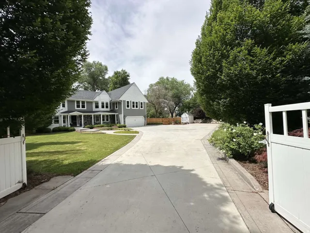 Spacious concrete driveway with decorative border and white privacy gate