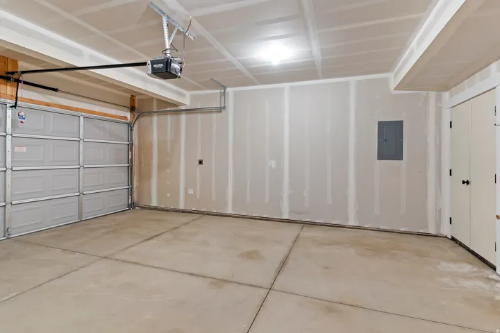 Spacious two-car garage featuring a concrete floor, an overhead garage door with an automatic opener, and a service door