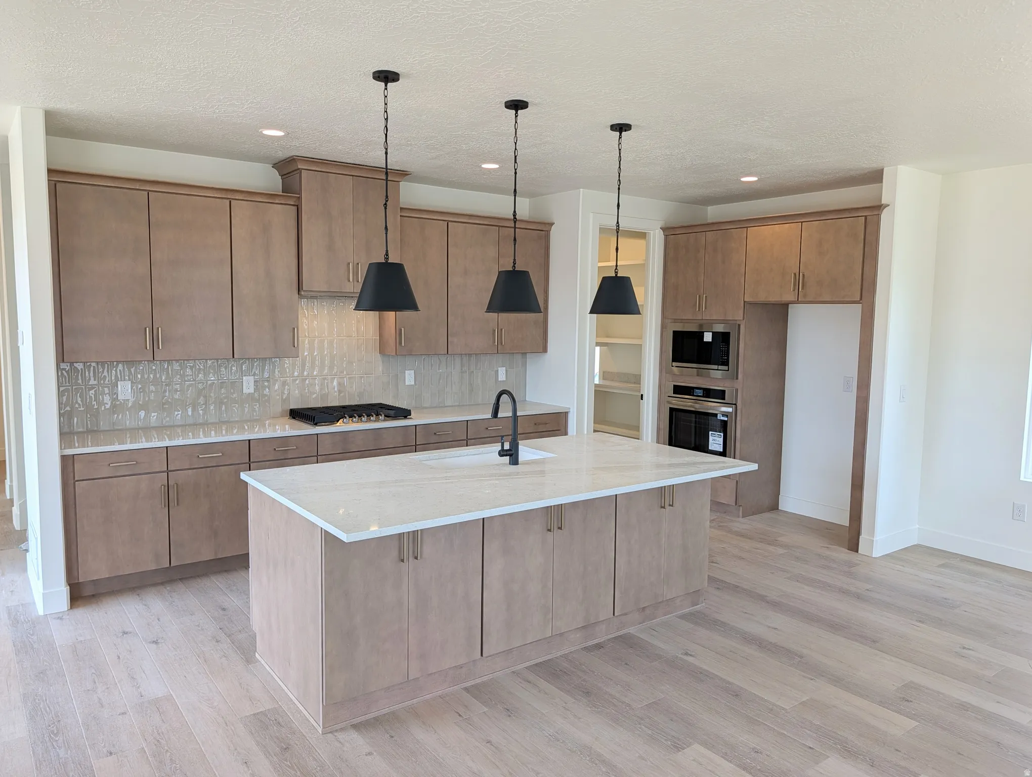 Contemporary kitchen featuring wood-finish cabinetry, light-toned countertops, and a full tile backsplash