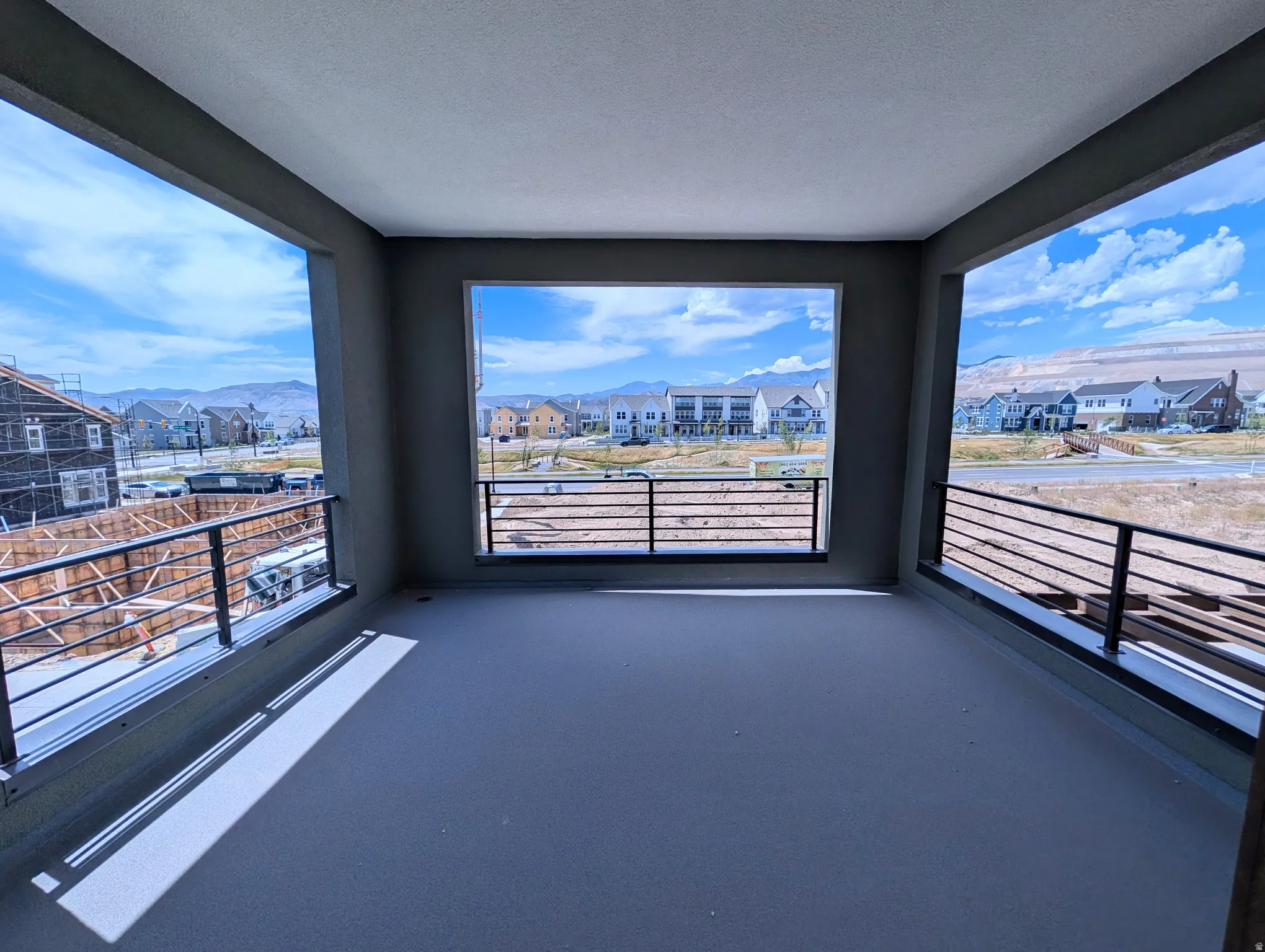 Expansive covered balcony featuring a concrete floor and contemporary black horizontal railings