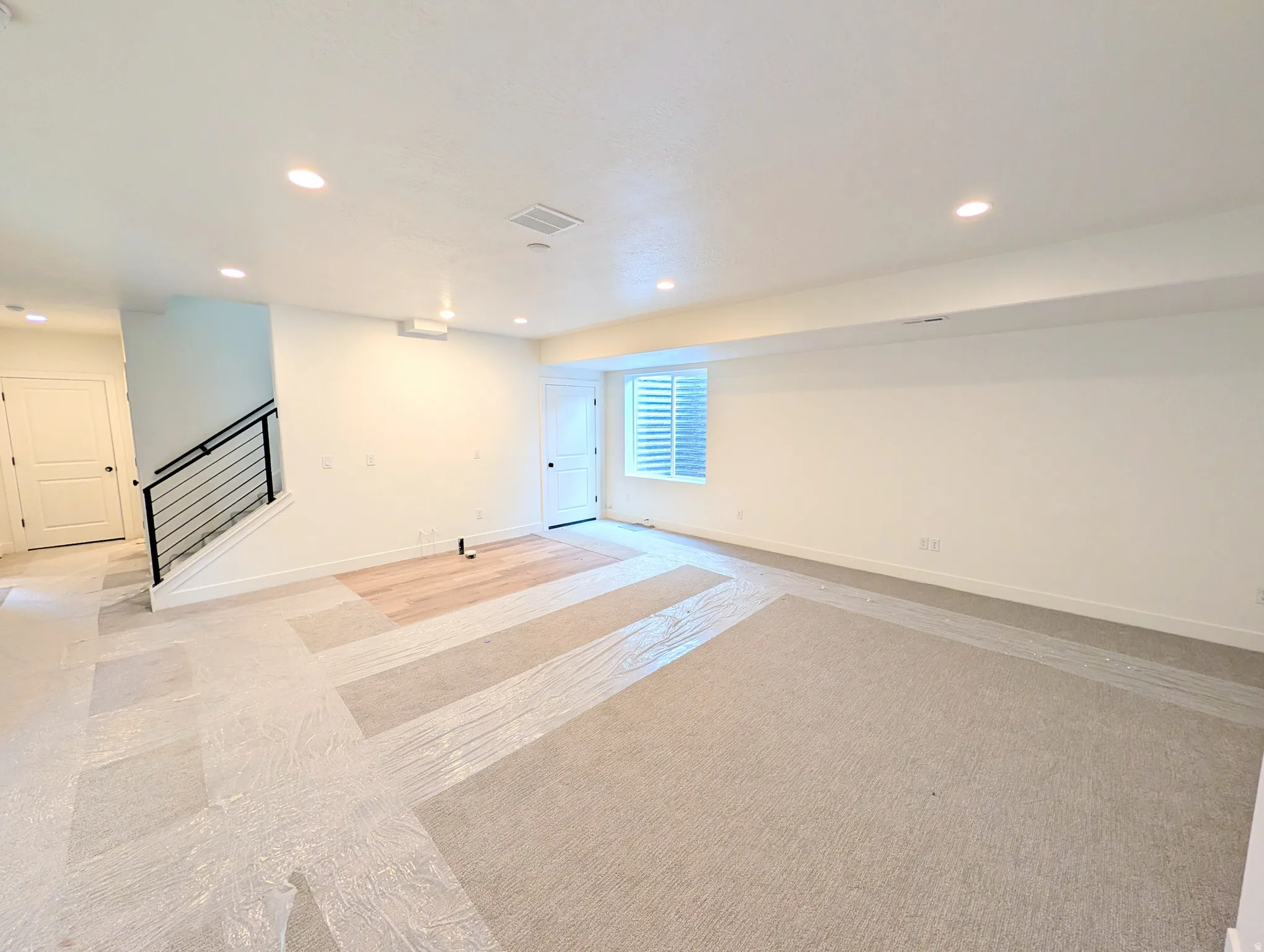 Spacious open-concept room featuring recessed lighting and a partially installed wood-finish flooring