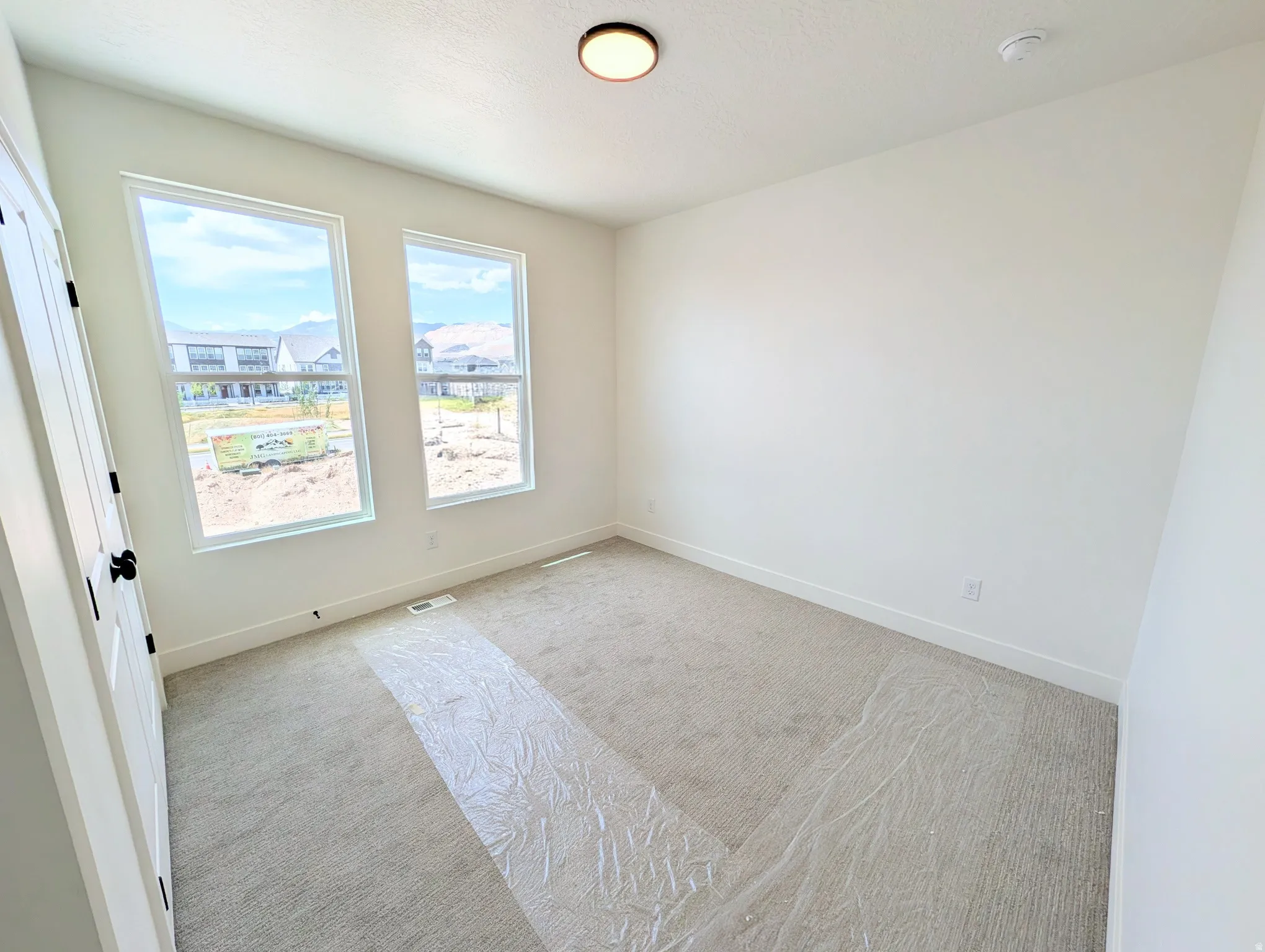 Bright room featuring two large windows, neutral wall paint, and light-colored carpeting