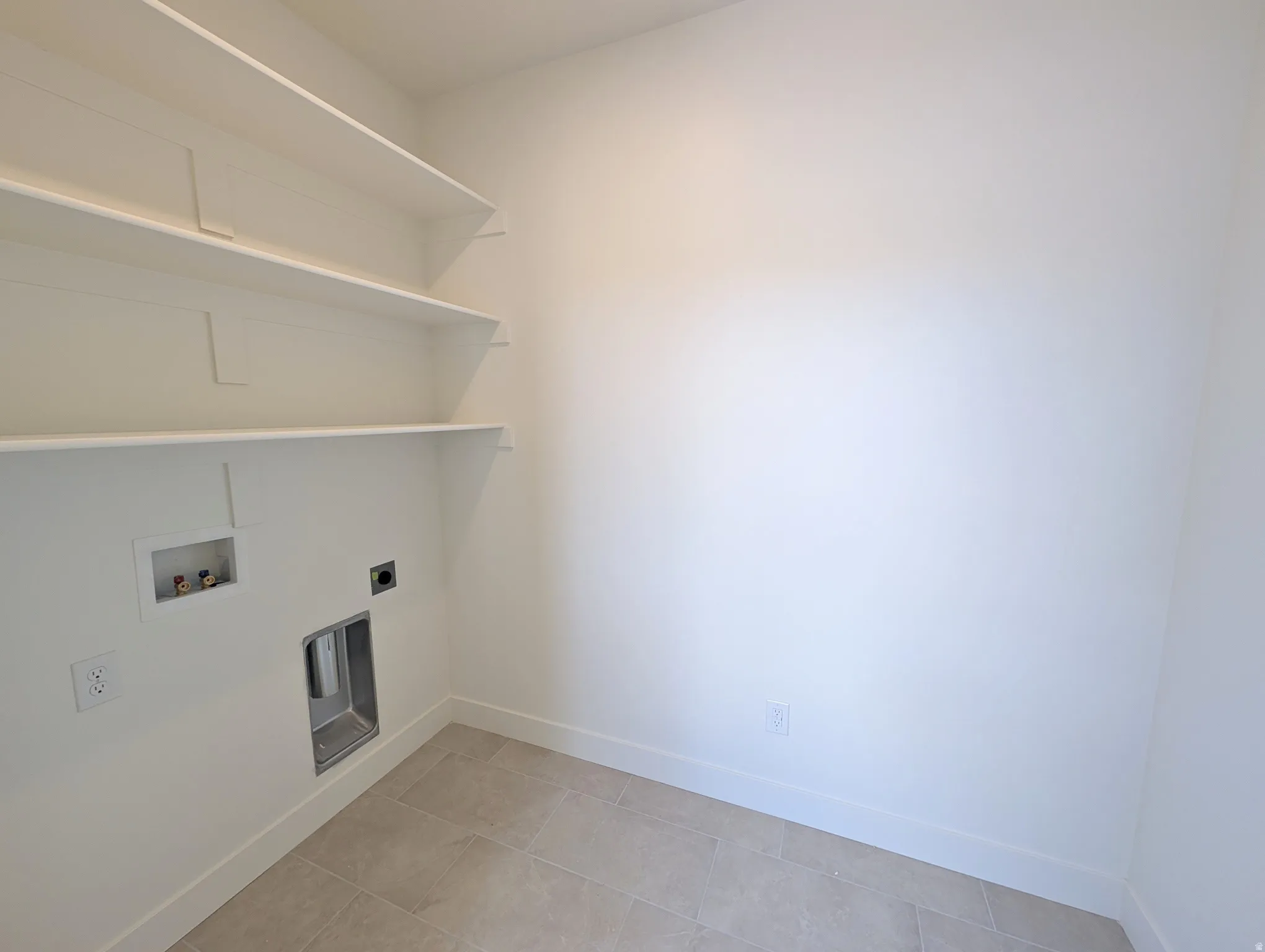 Laundry area featuring tiled flooring, white baseboards, and built-in shelving