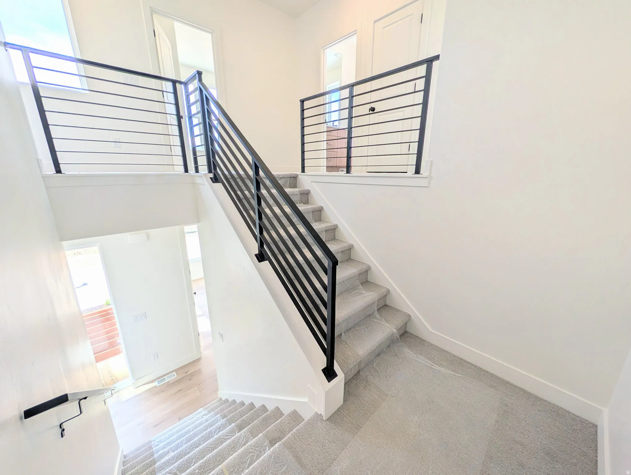 Modern two-story entryway featuring a carpeted staircase with contemporary horizontal metal railings