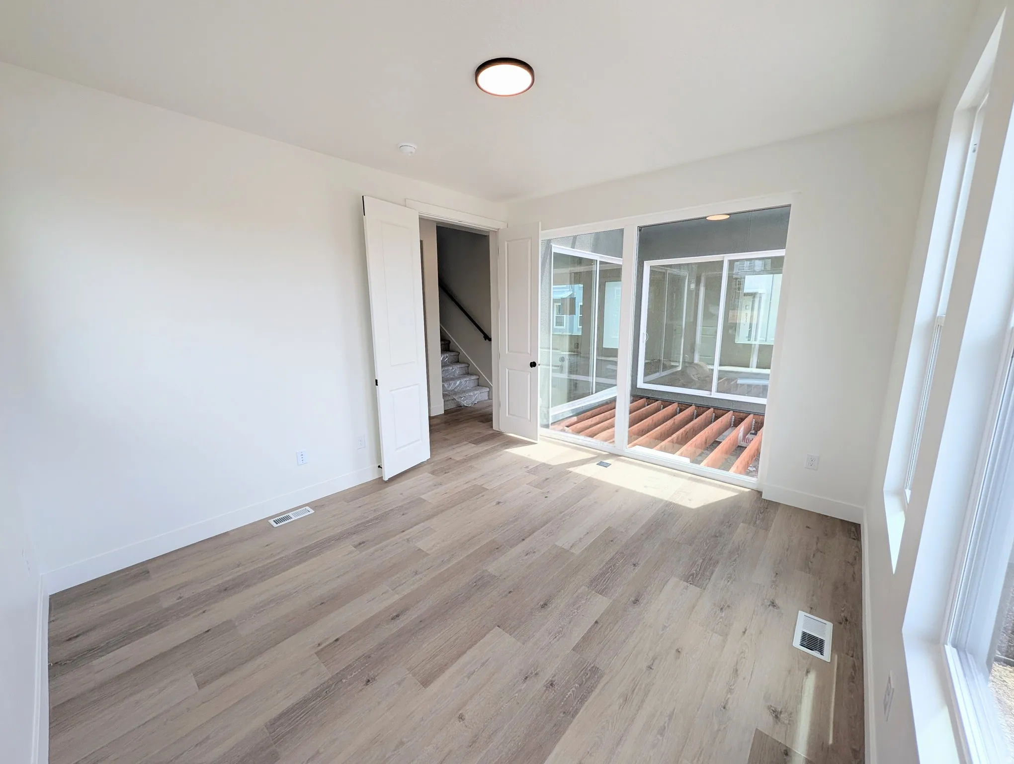 Spacious room featuring wood-finish flooring, white baseboards, and a contemporary flush-mount ceiling light