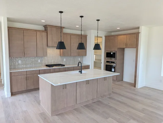 Contemporary kitchen featuring wood-finish cabinetry, light-toned countertops, and a full tile backsplash