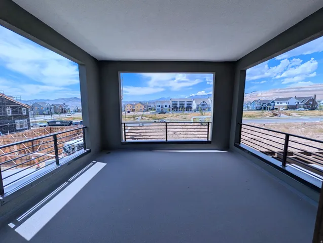 Expansive covered balcony featuring a concrete floor and contemporary black horizontal railings