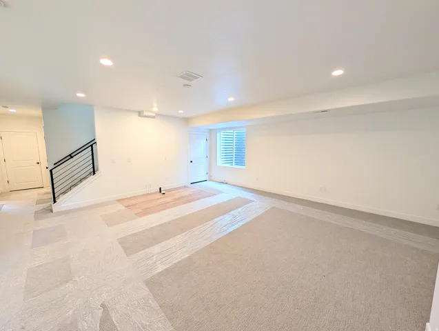 Spacious open-concept room featuring recessed lighting and a partially installed wood-finish flooring